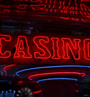 Neon lights display the word 'CASINO' in bright red, standing out against a dark background. The vibrant glow reflects a lively and bustling atmosphere.